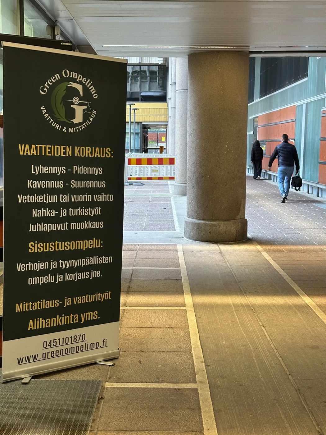 Vihreä Green Ompelimo -kyltti katetun kulkuväylän vieressä
